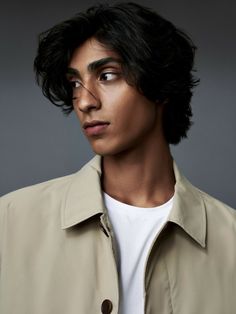 a young man with black hair wearing a trench coat