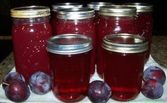 four jars filled with plums sitting on top of a table