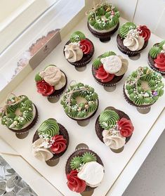 twelve decorated cupcakes are on display in a box