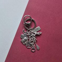 a metal keychain with charms on it sitting on a pink and white surface