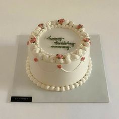 a white birthday cake with flowers on the top and happy birthday written in frosting