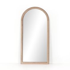 an arched wooden mirror against a white wall