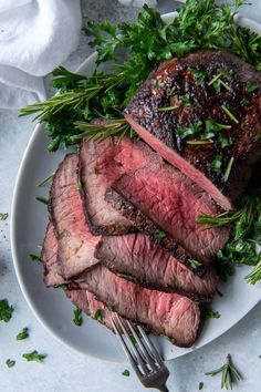 a piece of steak on a white plate with parsley garnish and a fork