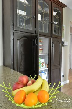 a bowl of fruit sitting on top of a counter next to a wooden hutch