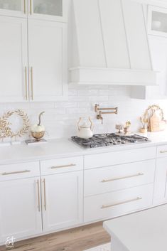 a kitchen with white cabinets and gold trim on the hood, stove top and oven