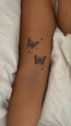 a woman's arm with two butterflies on it and stars in the sky above her