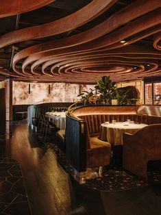 the interior of a restaurant with wooden ceilinging and leather booths, tables and chairs