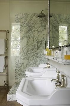 a bathroom with marble walls and flooring, two sinks in front of the mirror