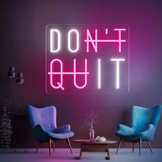 a neon sign that says don't quit next to two chairs and a table