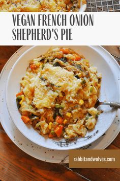 a white plate topped with pasta covered in cheese and veggies next to another plate filled with food