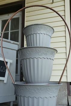 three large white flower pots sitting on top of each other in front of a house