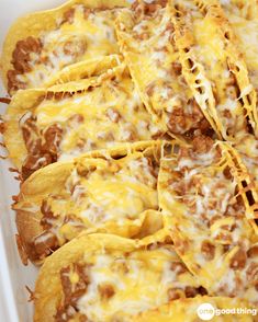 a casserole dish filled with cheese and ground beef, topped with tortilla shells