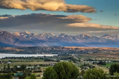 the mountains are covered in snow and clouds as seen from an overlook point on a sunny day