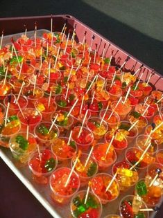 many jelly candies are arranged in small cups with toothpicks on the top