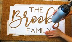 a person using a hair dryer on a door mat that says the brook family