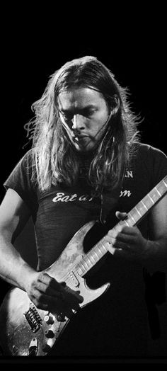 a man with long hair playing an electric guitar