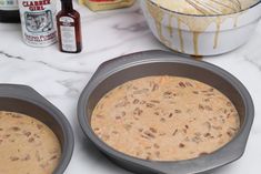 two pans filled with food sitting on top of a counter next to other ingredients