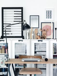 a desk with a chair, lamp and pictures on the wall in front of it