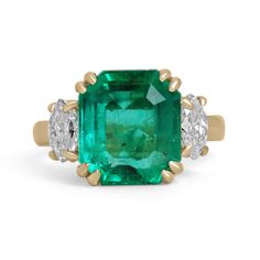 A dramatic emerald and diamond three-stone ring that is sure to turn heads anywhere you may take it. This classic piece features an exceptional 5.49-carat, Colombian emerald that appears much larger due to its widespread. The gemstone displays the most gorgeous, and fascinating dark vivid deep bluish-green color that hypnotizes you with its magic at first glance. An emerald of the finest quality, that is a true treasure to come across. Marquise cut diamond accents add eye-catching sparkle, as they sit on either side of the glamorous center stone. Double and single claw prong set in glistening solid 18K yellow gold. A 1 of 1 three-stone ring.  Setting Style: Double Prong Setting Material: 18K Yellow Gold Setting Weight: 8.0 Grams Main Stone: Emerald Shape: Emerald Cut Weight: 5.49-Carats Cl Luxury Vintage Three-stone Emerald Ring, Luxury Vintage Rectangular Emerald Ring, Three Stone Emerald Cut Ring, Antique Emerald Ring, 3 Stone Diamond Ring, Diamond Three Stone Ring, 3 Stone Ring, Emerald Cut Rings, 3 Stone Rings