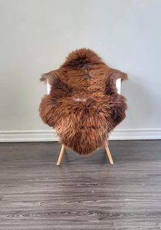 a brown chair sitting on top of a hard wood floor next to a white wall