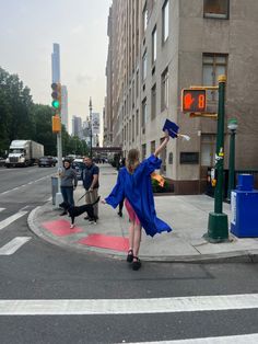 a woman in blue graduation gown throwing her cap into the air