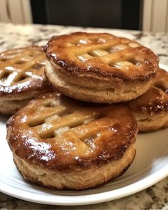 four small pies on a white plate sitting on a table