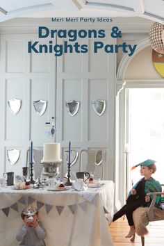 two children sitting at a table in front of a white wall with dragon and knights party decorations