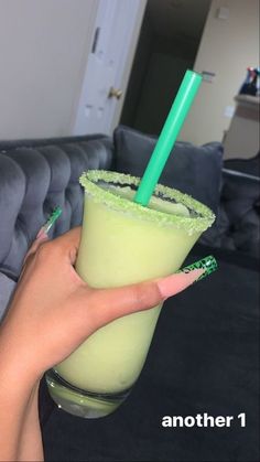 a person holding a green drink in their hand