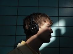 a man with headphones standing in front of a tiled wall