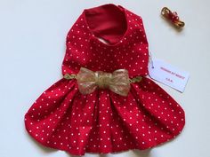 a red dress with white polka dots and a gold bow on the collar is next to a pair of baby shoes