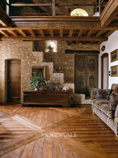 a living room with wood flooring and stone walls, along with an old fashioned couch