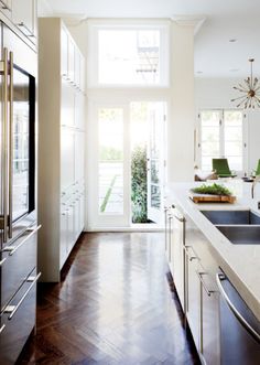 a kitchen with wood floors and stainless steel appliances in front of an open door that leads to the outside