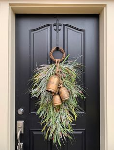 a black front door with a wreath and two bells hanging on it's side