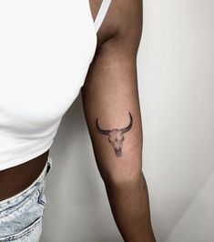 a woman's arm with a tattoo on it that has a bull skull on it