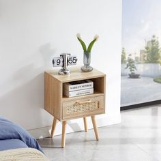 a nightstand with two flowers on it next to a bed