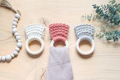 three crocheted items are sitting on a table next to a plant and beaded necklace