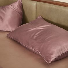 two pink pillows on a bed with brown sheets and pillow cases in the corner,