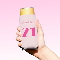 a person holding up a pink and white can with the number 21 printed on it