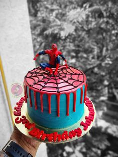 a spiderman cake is being held by someone