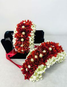 two red and white flowers with pearls on them are sitting next to a black box