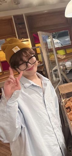 a young boy wearing glasses standing in front of doughnuts