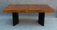 a wooden table sitting on top of a blue carpeted floor next to a gray wall