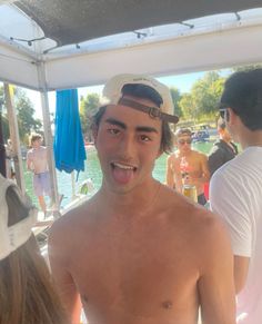 a shirtless man making a funny face while standing in front of people on a boat