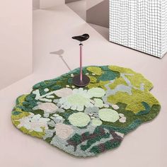 a green rug with flowers on it and a black object in the middle next to it