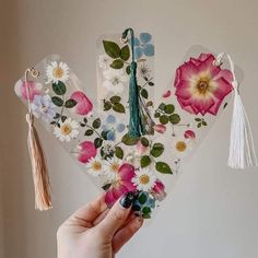 a person holding up some flowers and tassels to show off their crafting skills