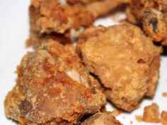 some fried food on a white plate with crumbs and seasoning sprinkles