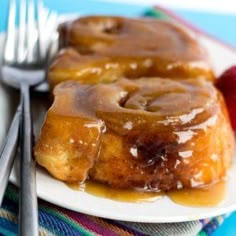 a white plate topped with cinnamon rolls covered in icing next to two strawberries