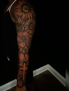 a woman's arm with flowers and a cross tattoo on the left side of her leg