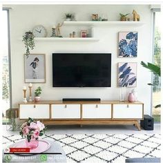 a flat screen tv sitting on top of a wooden entertainment center in a living room