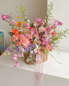 a basket filled with lots of flowers sitting on top of a white counter next to a painting